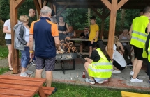 GRUPA LUDZI WSPÓLNIE PIECZE KIEŁBASKI PRZY OGNISKU 
