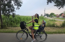 KOBIETA JEDZIE NA ROWERZE Z DZIECKIEM W FOTELIKU