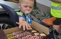 DZIECKO SIEDZI W FOTELIKU NA ROWERZE I WYCIĄGA RĄCZKE PO BATANIKI GRZEŚKI
